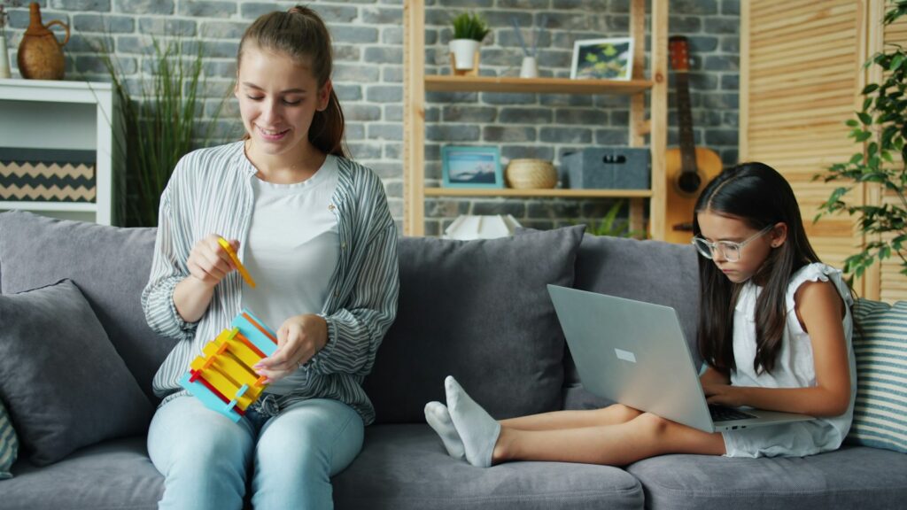 Mother and daughter learning together at home on the couch