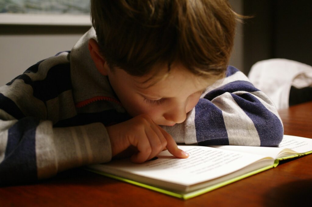 Young boy reading a book at a table