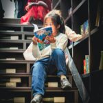 Young girl reading a book in a library